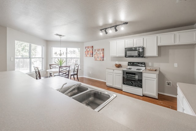 kitchen with white cabinets, decorative light fixtures, light hardwood / wood-style floors, and white range with electric stovetop