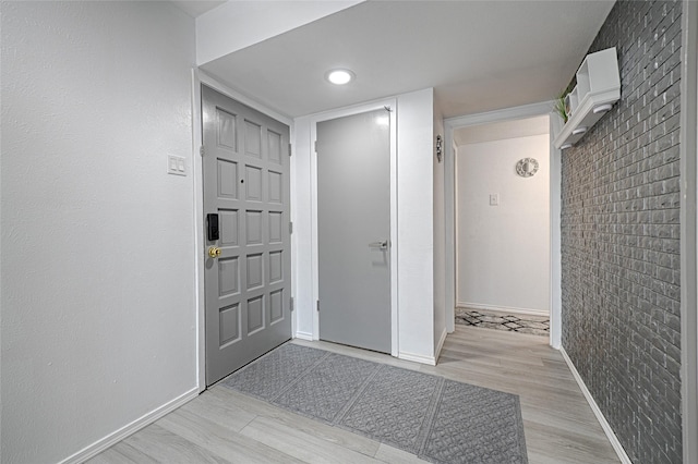 entrance foyer with light wood-type flooring and brick wall