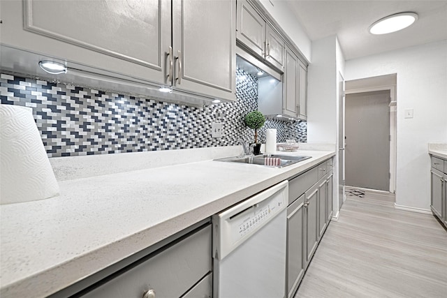 kitchen with gray cabinetry, white dishwasher, sink, light hardwood / wood-style flooring, and decorative backsplash