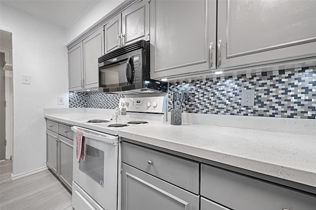 kitchen with decorative backsplash, gray cabinets, white electric stove, and light hardwood / wood-style floors