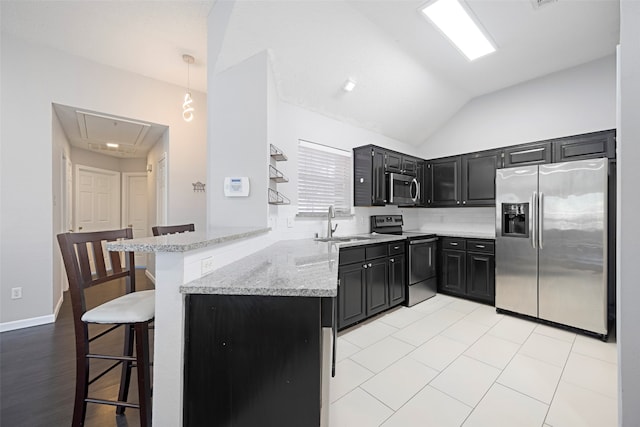 kitchen with stainless steel appliances, sink, kitchen peninsula, a breakfast bar area, and decorative light fixtures