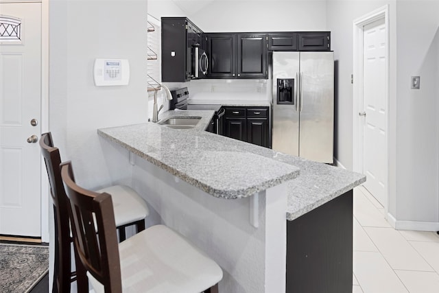 kitchen featuring stainless steel appliances, a breakfast bar, light stone counters, kitchen peninsula, and light tile patterned floors