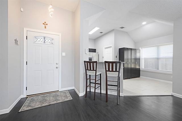 foyer featuring dark wood-type flooring, lofted ceiling, and a textured ceiling