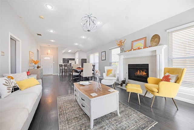 living room featuring a fireplace, plenty of natural light, dark wood-type flooring, and an inviting chandelier