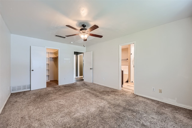 unfurnished bedroom with light carpet, a walk in closet, ceiling fan, connected bathroom, and a closet