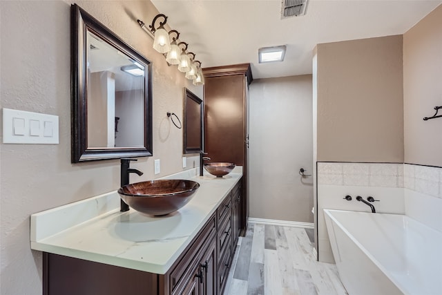 bathroom featuring wood-type flooring, vanity, and a tub to relax in