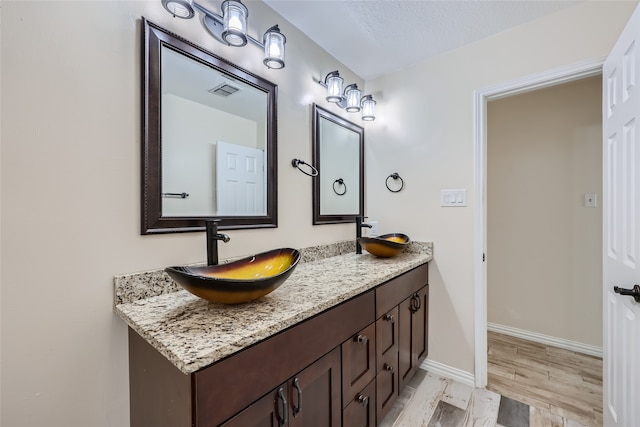 bathroom with hardwood / wood-style floors, vanity, and a textured ceiling