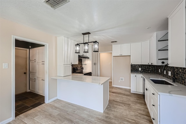 kitchen with appliances with stainless steel finishes, light stone counters, sink, pendant lighting, and white cabinetry