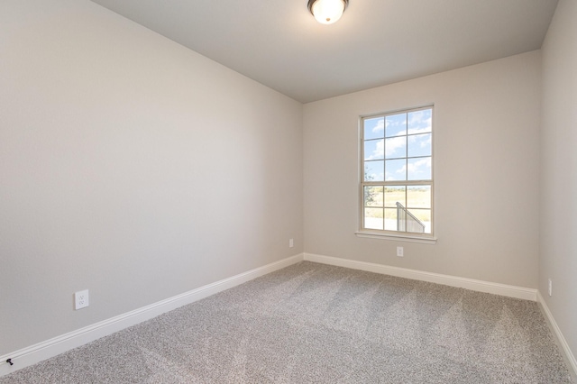 carpeted empty room featuring baseboards and vaulted ceiling