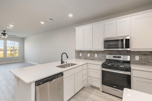 kitchen with a sink, light countertops, stainless steel appliances, light wood-type flooring, and visible vents