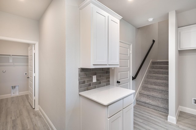corridor with stairway, baseboards, and light wood finished floors
