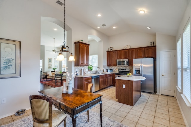 kitchen featuring ceiling fan, tasteful backsplash, pendant lighting, a kitchen island, and appliances with stainless steel finishes