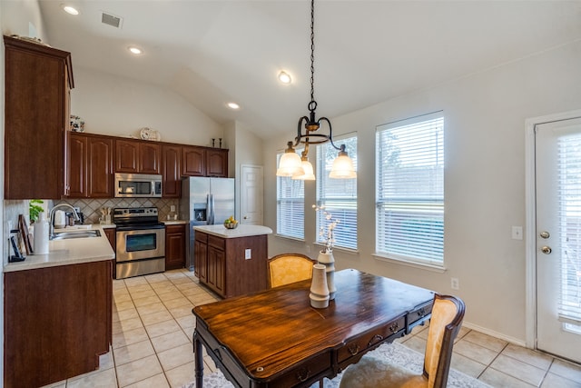 kitchen with sink, vaulted ceiling, decorative light fixtures, light tile patterned flooring, and appliances with stainless steel finishes