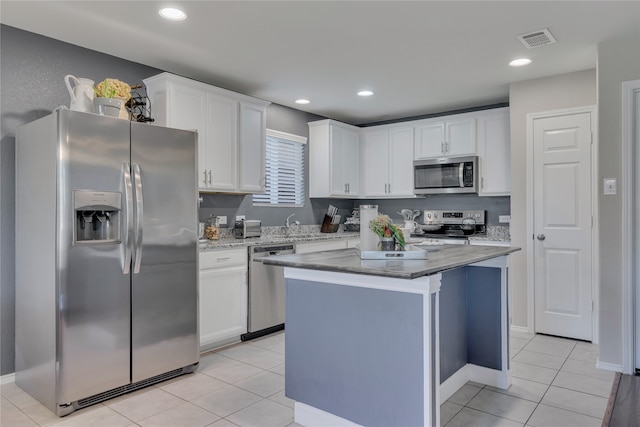 kitchen featuring a kitchen island, white cabinetry, stainless steel appliances, and light tile patterned floors