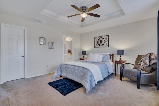 carpeted bedroom with ceiling fan, a raised ceiling, ensuite bathroom, and crown molding