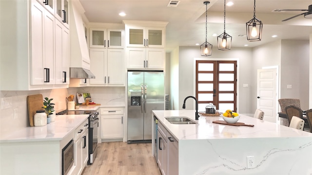 kitchen with appliances with stainless steel finishes, white cabinetry, sink, and an island with sink