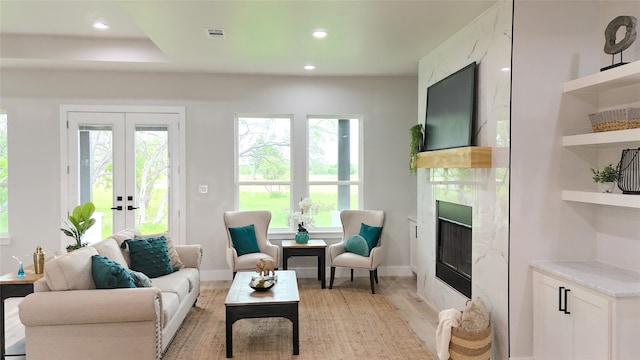 living room with a premium fireplace, french doors, and light hardwood / wood-style floors