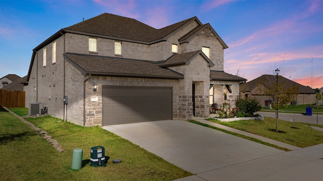 french country inspired facade with central AC unit, a garage, and a lawn