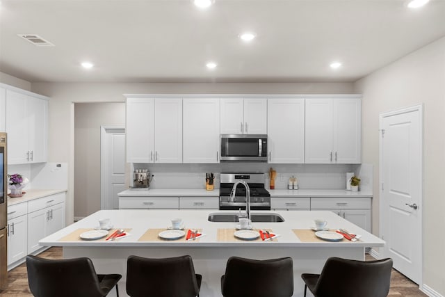 kitchen with white cabinetry, a kitchen island with sink, stainless steel appliances, and sink