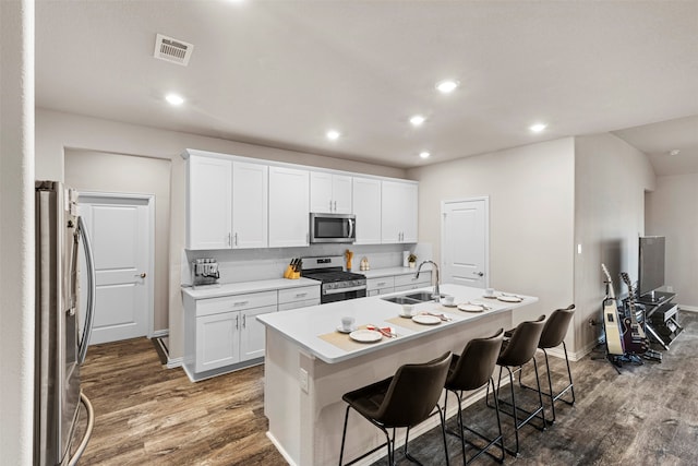 kitchen with a center island with sink, sink, stainless steel appliances, and light hardwood / wood-style floors