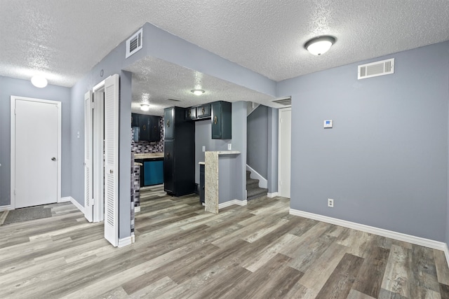 interior space featuring a textured ceiling and light hardwood / wood-style floors