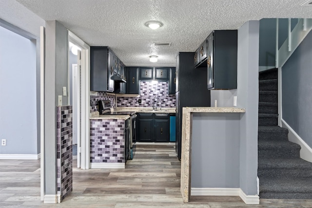 kitchen with stainless steel electric range oven, a textured ceiling, and light hardwood / wood-style flooring