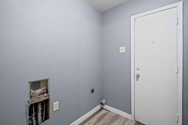 clothes washing area featuring hardwood / wood-style floors, hookup for a washing machine, a textured ceiling, and electric dryer hookup