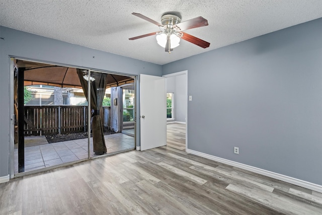 unfurnished room featuring ceiling fan, wood-type flooring, and a textured ceiling