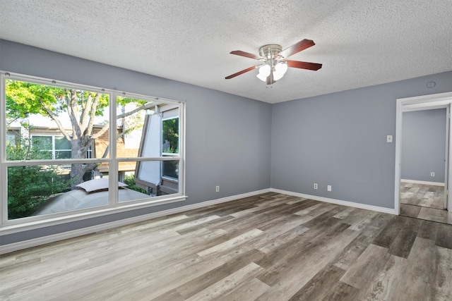 empty room with wood-type flooring, ceiling fan, and a textured ceiling