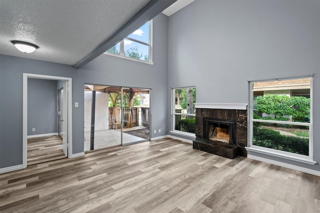 unfurnished living room with light wood-type flooring, a fireplace, and high vaulted ceiling