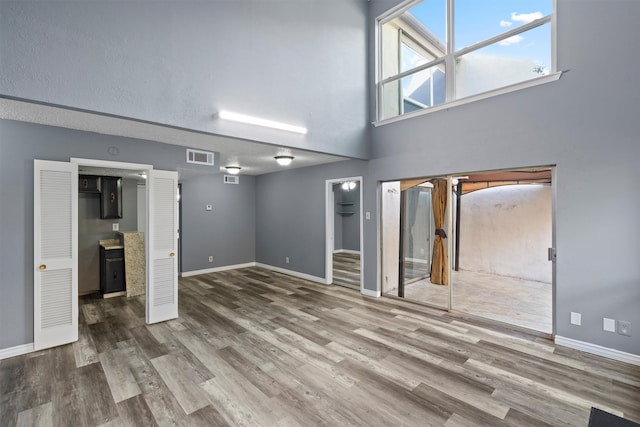 unfurnished living room featuring a high ceiling and wood-type flooring