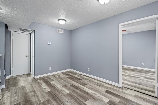 unfurnished room with wood-type flooring and a textured ceiling