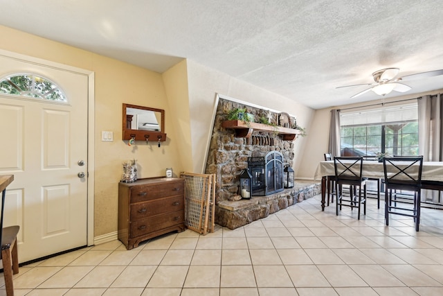 dining space with a textured ceiling, ceiling fan, a fireplace, and a wealth of natural light