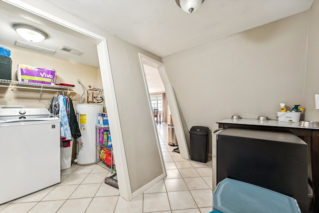 clothes washing area featuring water heater, light tile patterned flooring, and washer / clothes dryer