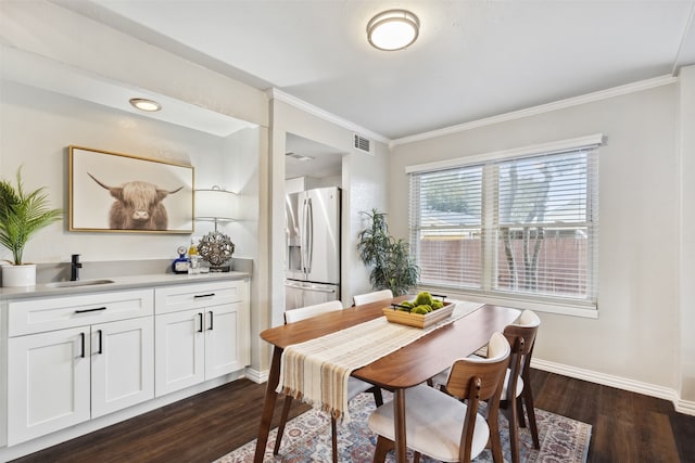 dining space featuring sink, dark wood-type flooring, and ornamental molding