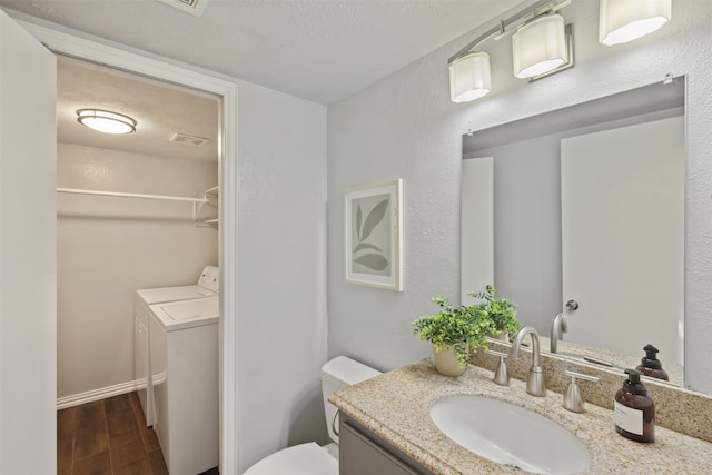 bathroom with hardwood / wood-style floors, vanity, toilet, independent washer and dryer, and a textured ceiling