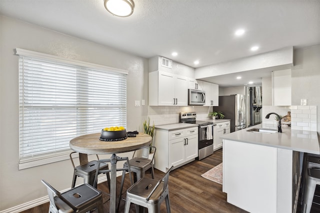 kitchen with sink, decorative backsplash, appliances with stainless steel finishes, dark hardwood / wood-style flooring, and white cabinetry