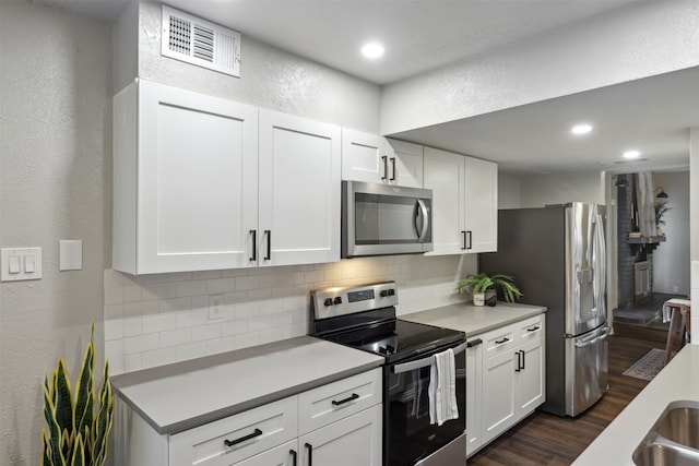 kitchen featuring stainless steel appliances, white cabinetry, tasteful backsplash, and dark wood-type flooring