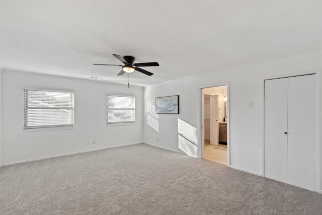 unfurnished bedroom with ceiling fan, light carpet, and connected bathroom