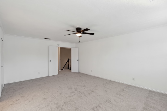 carpeted empty room featuring ceiling fan and crown molding