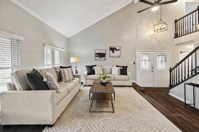 living room with hardwood / wood-style floors, ceiling fan with notable chandelier, high vaulted ceiling, and ornamental molding