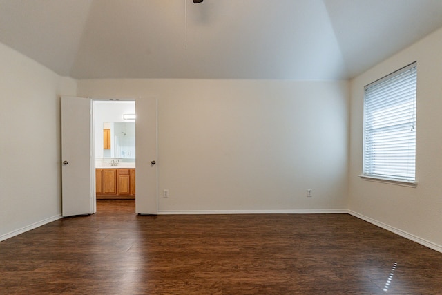 spare room with dark wood-type flooring and lofted ceiling