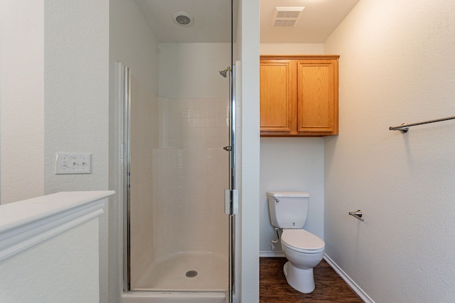 bathroom featuring toilet, a shower with shower door, and hardwood / wood-style floors