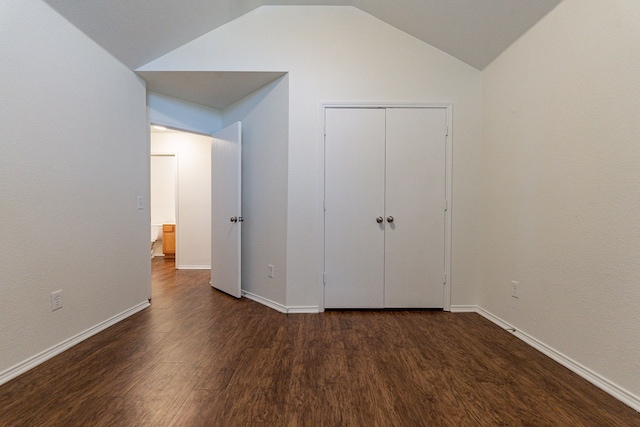 unfurnished bedroom featuring lofted ceiling, dark hardwood / wood-style floors, and a closet