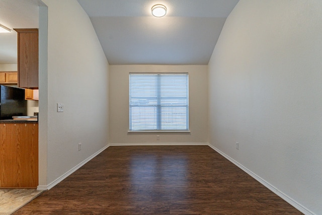 empty room featuring vaulted ceiling and dark hardwood / wood-style flooring