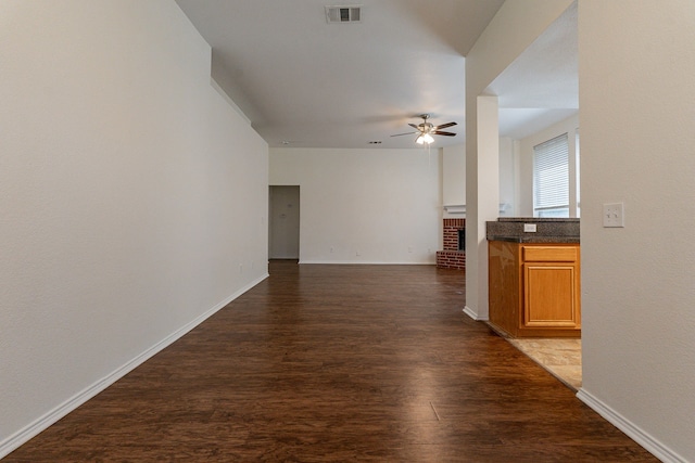 unfurnished living room featuring dark wood-type flooring, ceiling fan, and a fireplace