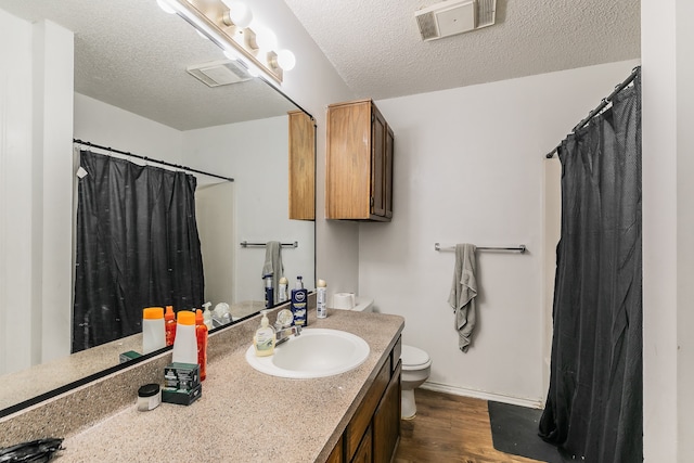 bathroom with hardwood / wood-style flooring, vanity, toilet, and a textured ceiling