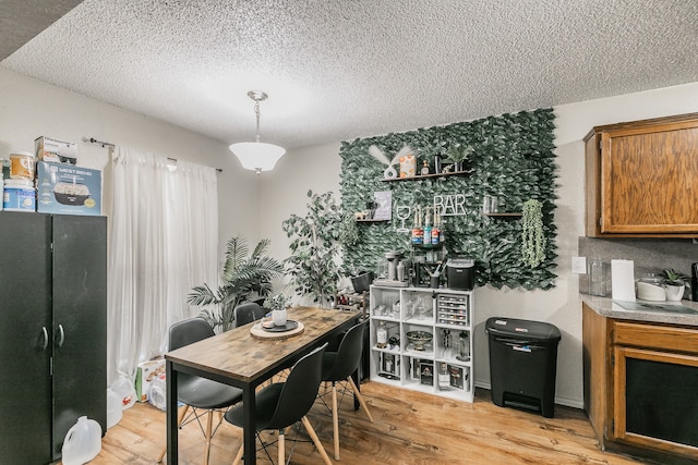 dining space with a textured ceiling and light hardwood / wood-style flooring