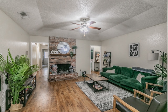 living room with a fireplace, a textured ceiling, and wood-type flooring