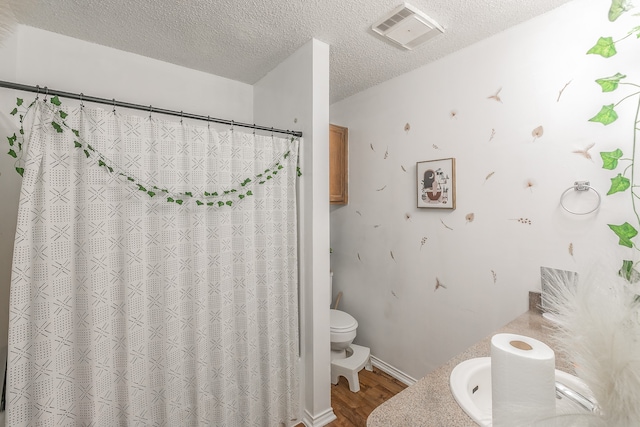 bathroom with hardwood / wood-style floors, vanity, a textured ceiling, and toilet